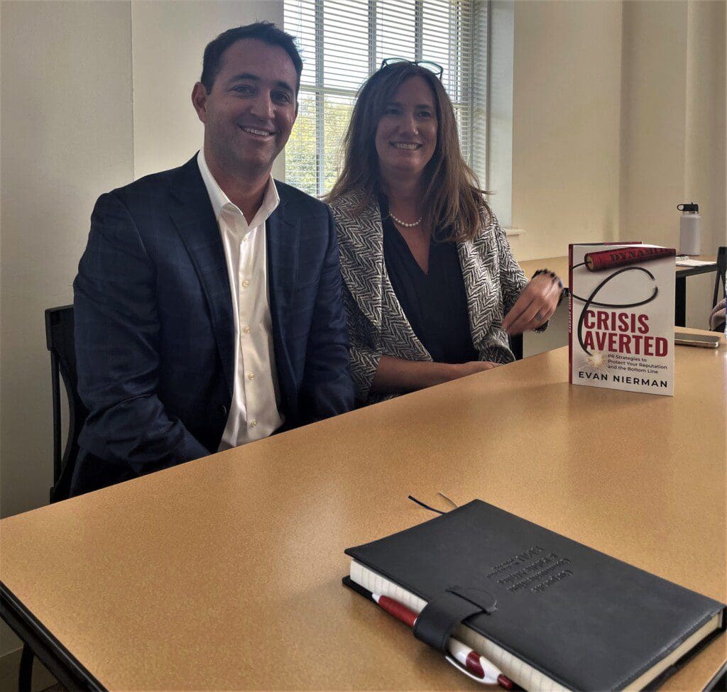 Image is of Evan Nierman and Prof. Kim Commerato Lance at a table with Nierman's book, "Crisis Averted"